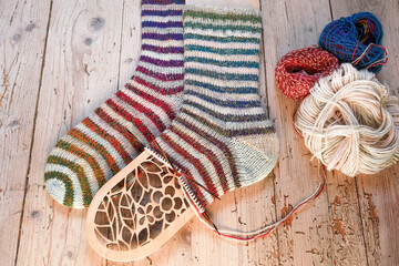 One pair of colourful handknitted socks with ombre rainbow stripes sockyarn laying on vintage...