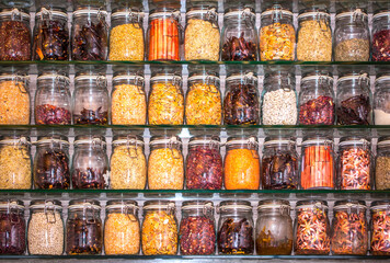 Spices set. Glass jars with seasonings and cereals on the shelves. Many different seasonings in the cupboard in the kitchen. Background with copy space.