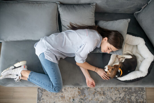 A Young Woman Lying Next To Her Puppy And Having A Nap