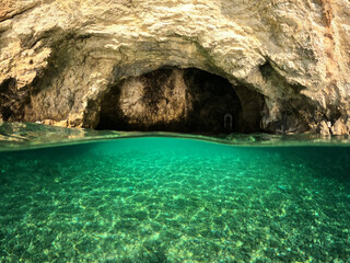 Underwater split photo of paradise sea cave arch with crystal clear emerald sea in Mediterranean destination island