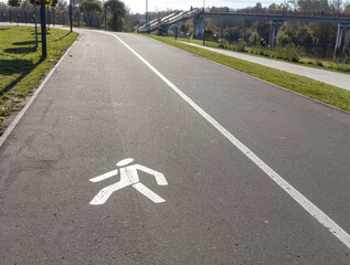 White road markings for pedestrians and cyclists.The walking and cycling paths in the park are...