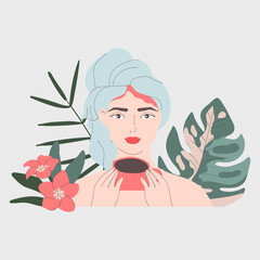 Woman is drinking coffee. Head in a towel after a shower. Tropical leaves and flowers. Morning routine