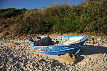 Barca de madera abandonada en una playa cerca de Tarifa, costa de Andalucía, España. Estos barcos llamados 