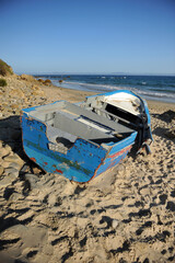 Wooden boat wrecked on a beach near Tarifa, coast of Andalusia, southern Spain. These boats called...