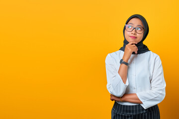 Pensive young Asian woman looks seriously thinking about a question on yellow background
