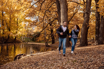 Fototapeta premium Young people man and woman throw up autumn leaves in autumn in the park during leaf fall