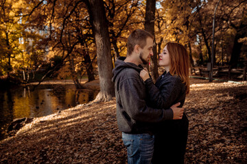 Fototapeta premium Young people man and woman throw up autumn leaves in autumn in the park during leaf fall