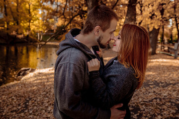 Young people man and woman throw up autumn leaves in autumn in the park during leaf fall