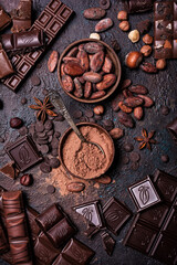 Chocolate background with lots of bars, nuts, cocoa beans and powder