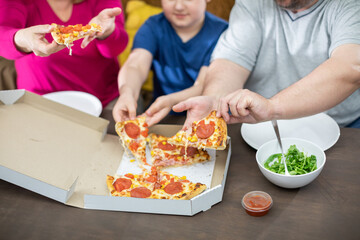 Obraz na płótnie Canvas The family divides the pizza slices among themselves.