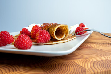 Traditional Finnish cuisine: Finnish pancakes on a plate with whipped cream and raspberry jam on the side