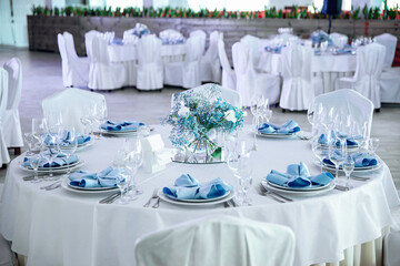 The banquet hall with round tables. Restaurant banquet hall with served decorated wedding tables. Round white table with graceful compositions of fresh flowers.