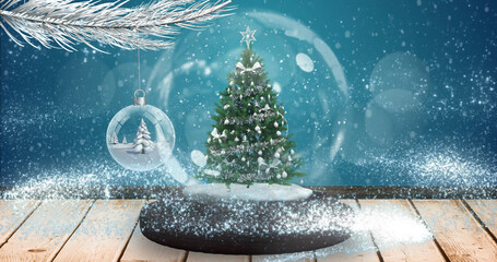 Image of snow falling and glowing spots over snow globe with tree on blue background