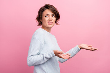 Photo of unhappy upset clueless young woman shrug shoulders look empty space isolated on pink color...
