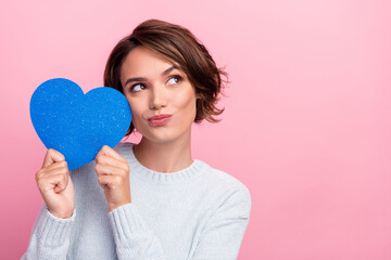 Fototapeta na wymiar Photo of romantic lady hold blue heart figure look empty space wear blue sweater isolated pink color background