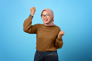 Fototapeta premium Portrait of cheerful beautiful Asian woman rejoicing celebrating luck on blue background