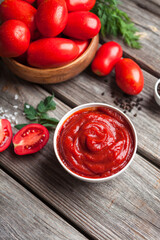 Homemade tomato sauce in white bowl, fresh tomatoes, spices and herbs. Food background