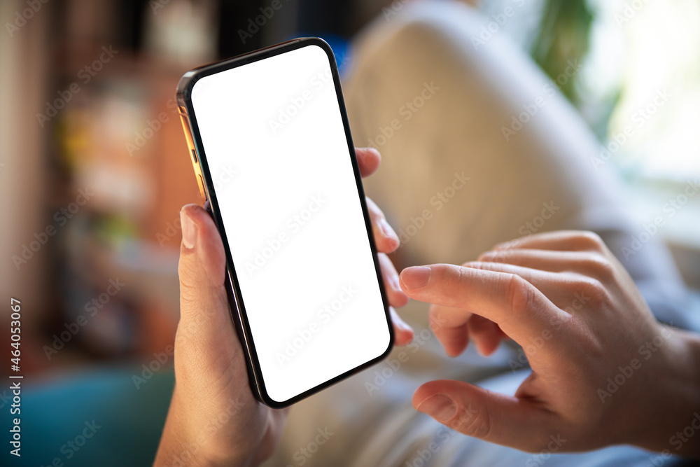Poster man using smartphone blank screen frameless modern design while lying on the sofa in home interior -