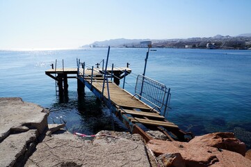 Old weathered partially destroyed pier detail and beautiful sea water surface, selective focus
