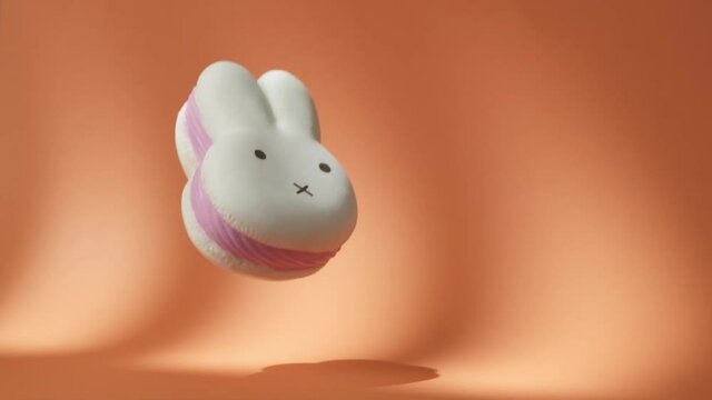 Big White and Pink Spongy Rabbit falling down on the orange background. Hare-Shaped squishy Toy Bounces Off Orange Surface in Slow Motion. 500 fps