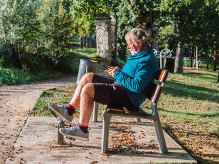 concentrated senior man outdoors uses phone while exercising