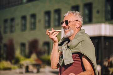 Happy male recording an audio reply on his smartphone