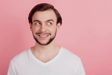 Portrait of positive curious guy look side empty blank space on pink background