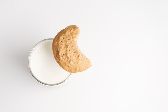 Top Down View On Bitten Off Cookie On Glass Of Milk On White Background. Selective Focus