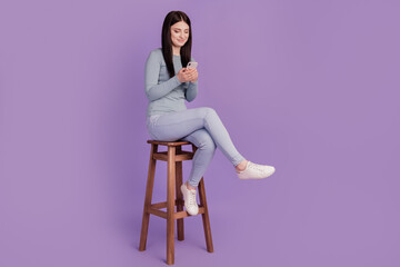 Full size profile side photo of young girl look browse cellphone sit stool isolated over purple...
