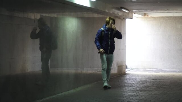 Red-haired young guy is waiting for someone in the underpass