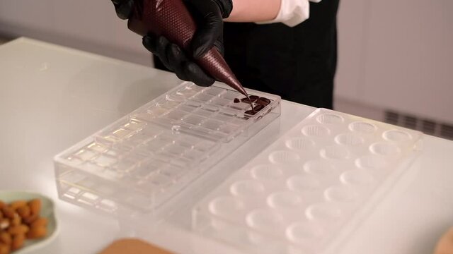 Pouring melted hot chocolate into a plastic mold. Making homemade handcrafted chocolate