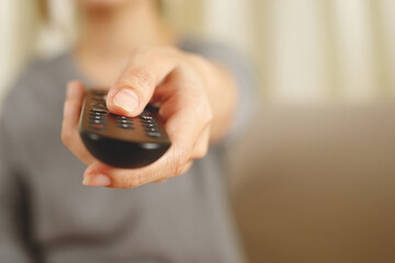 Woman presses online TV remote at home