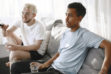 Obraz premium Male friends watching tv together in a bright room