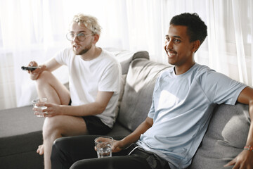 Male friends watching tv together in a bright room