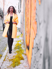 tall woman wearing yellow coat on the street