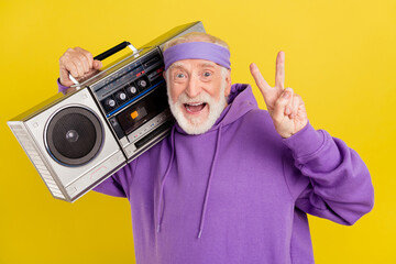 Photo of aged man hold on shoulder boombox show peace v-symbol sound isolated over yellow color...
