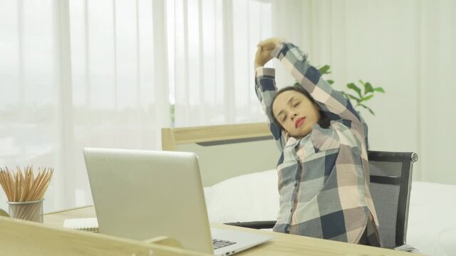 Relax happy latin young business woman working from home, stretching. People typing on computer laptop notebook device on social media internet technology with a bed in bedroom at home. Lifestyle