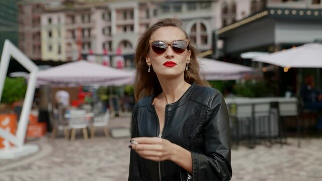sexy woman is walking alone in downtown in daytime, strolling and smoking cigarette