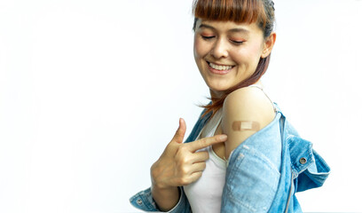 Asian woman smiling using adhesive bandage plaster at arm gesture after injection vaccine on a white isolated background. Female cheerful and confident in getting vaccinated against various diseases. - obrazy, fototapety, plakaty