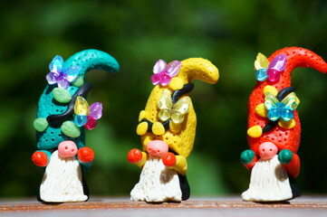 Three fabulous dwarfs made of plasticine decorated with toy butterflies. Close-up. Christmas decorations.