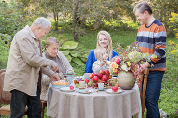happy family at  laid table with apple pie  in garden