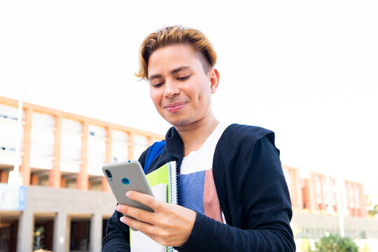 Smiling student browsing smartphone in campus