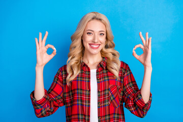 Photo of pretty charming young woman dressed checkered shirt smiling showing okey sign isolated blue color background