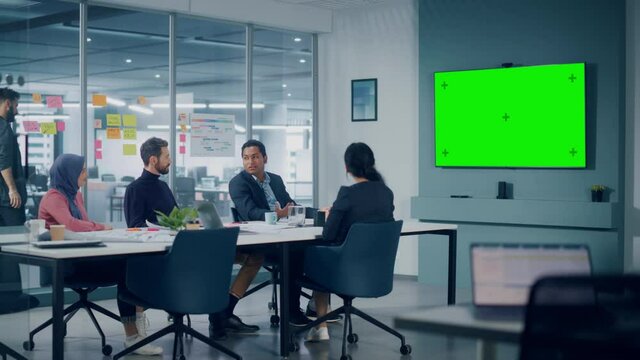 Businesspeople do Video Conference Call with Green Screen TV in Office Meeting Room. Diverse Team of Creative Entrepreneurs at Big Table have Discussion. Specialists work in Digital e-Commerce Startup