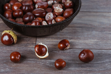 Close up view of chestnuts in a cast iron pan on a wooden background