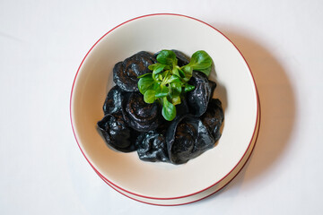 Black dumplings with pepper and herbs.