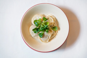 Dumplings with pepper and herbs on white plate.