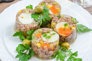 Jellied meat with pieces of meat with vegetables and herbs close-up