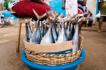 Basket with fresh fish placed on ground in local market in African village