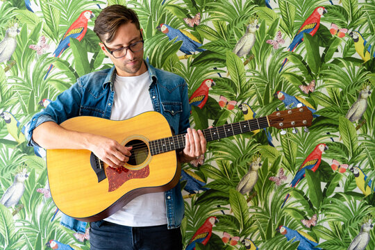 Guitarist performing melody against vivid paintings on wall
